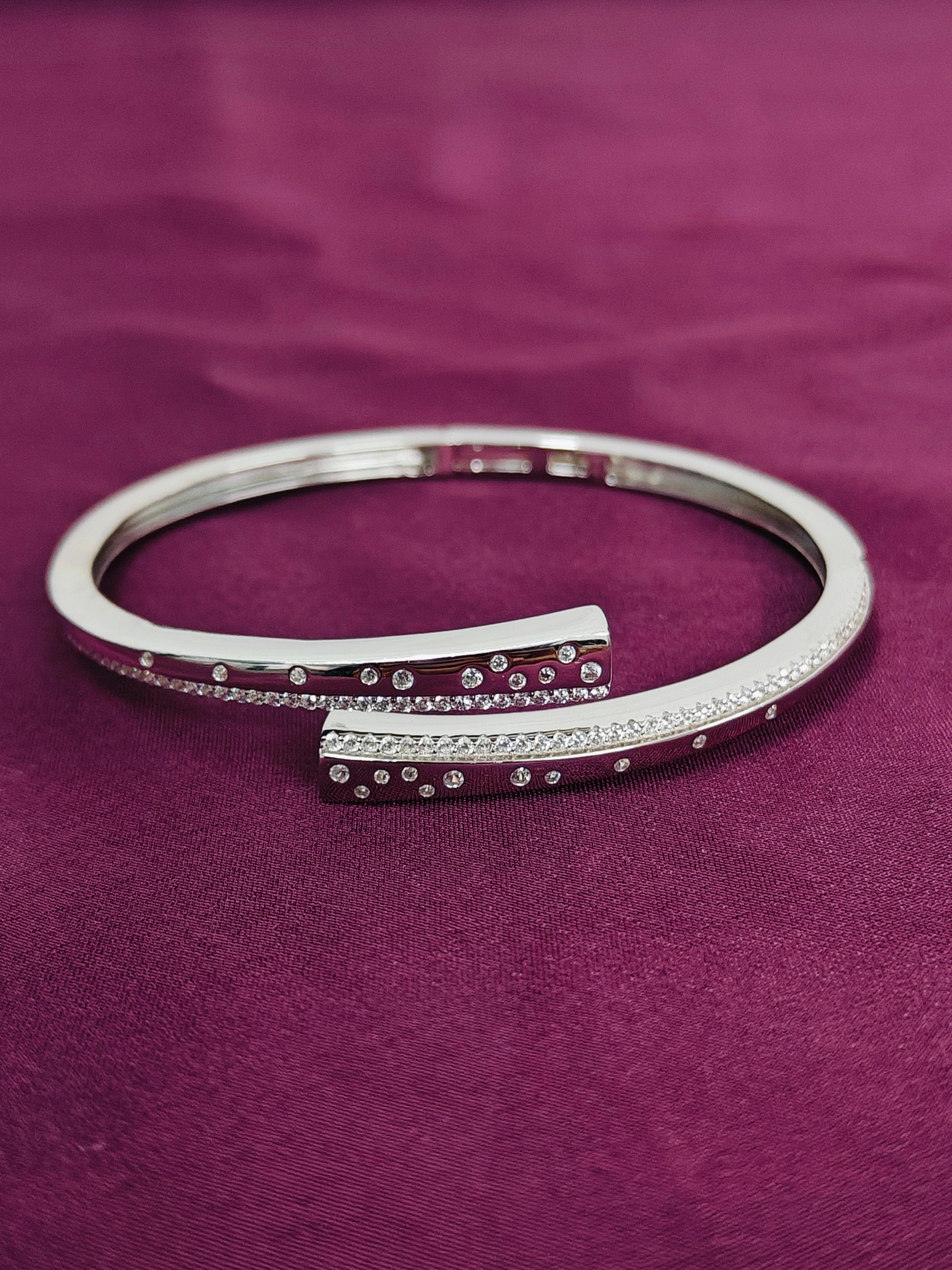 Silver bracelet with small stones on a purple fabric background